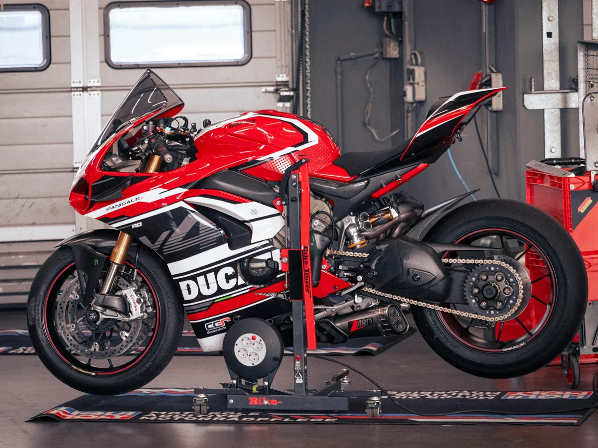 Motocykl sportowy przypięty na rolkach hamowni w hali warsztatu